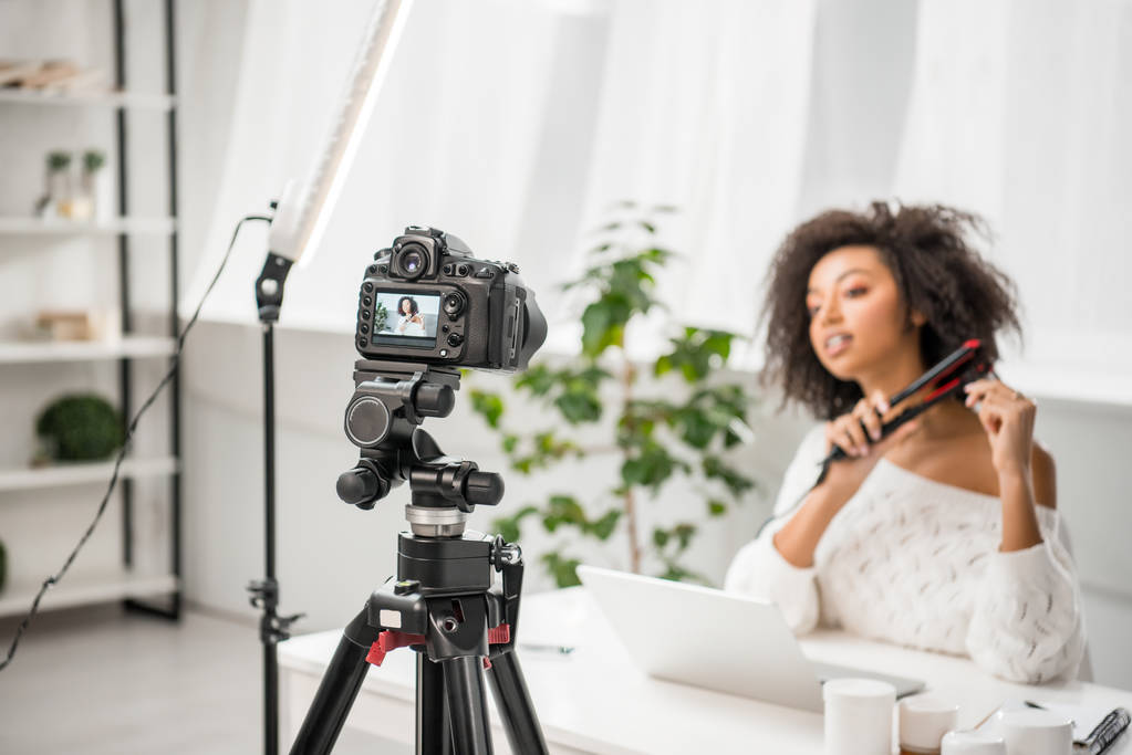 A woman with 4C hair using a hair straightener.