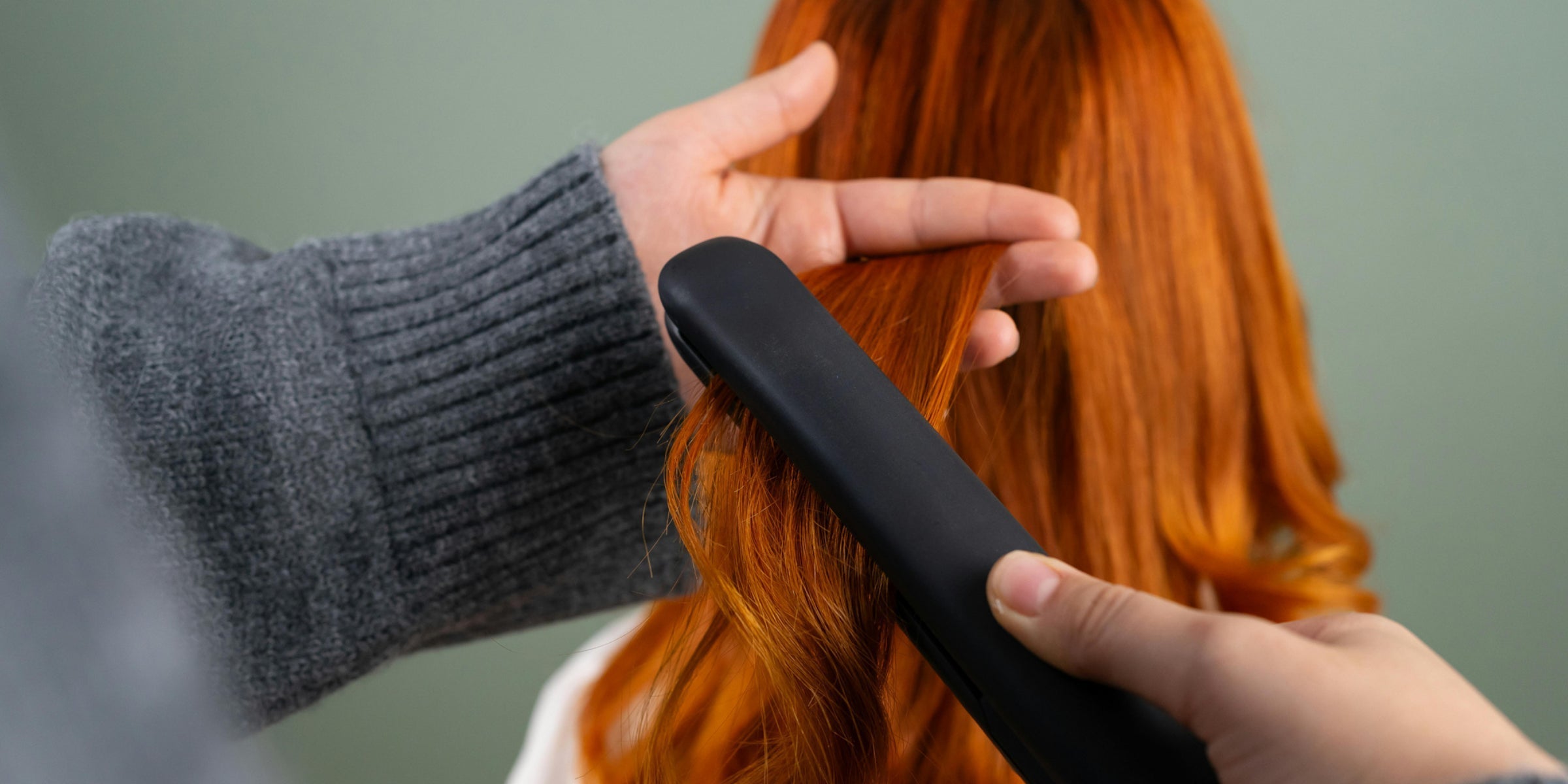  Curling long red hair with a flat iron.