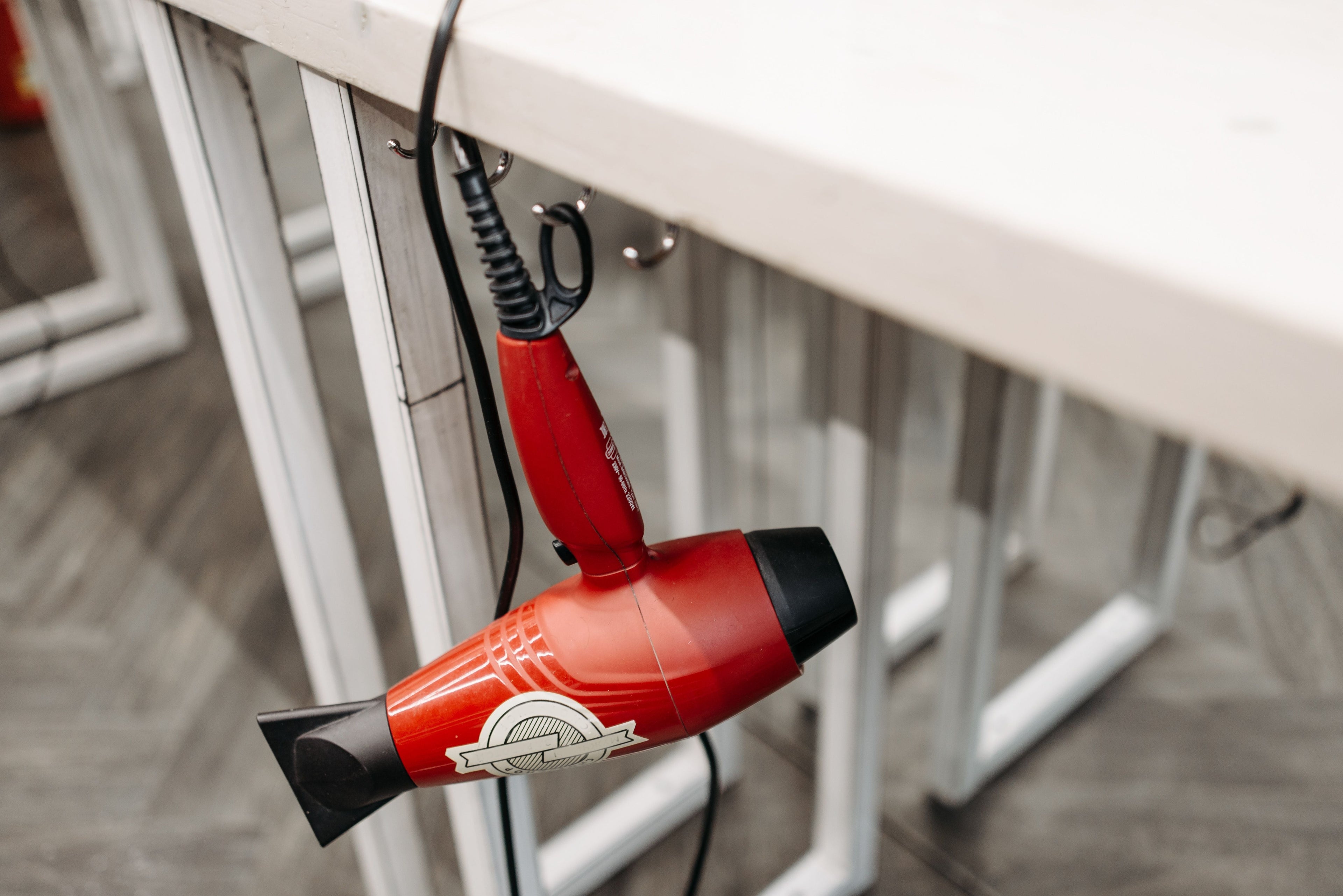 An overused hairdryer hanging from a table.